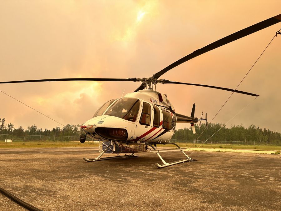 <who> Photo Credit: Saskatchewan Public Safety Agency</who> An orange-coloured haze, resulting from a nearby wildfire, is seen on a helipad in La Ronge, Sask., in an undated handout photo.
