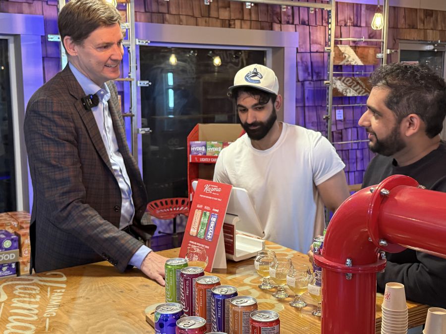 <who>Photo credits: Steve MacNaull/NowMedia Group</who>Premier David Eby, left, tastes Farming Karma sparkling pear soda with co-owners and brothers Sumeet and Abi Gill.