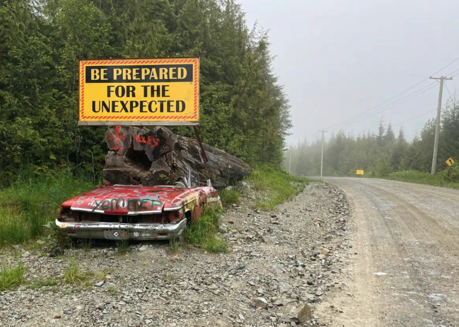 <who> Photo credit: LJI/Heather Nelson-Smith. </who> A crushed car sits beside the road to Holberg, BC, on the way to San Josef Bay placed by the logging company to warn drivers.