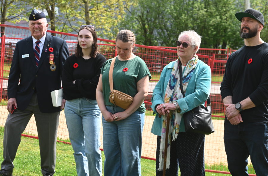 <who> Photo credit: Abby Luciano / North Shore News </who> A member of the Legion joins the family of Bob Reid during Thursday's ceremony.