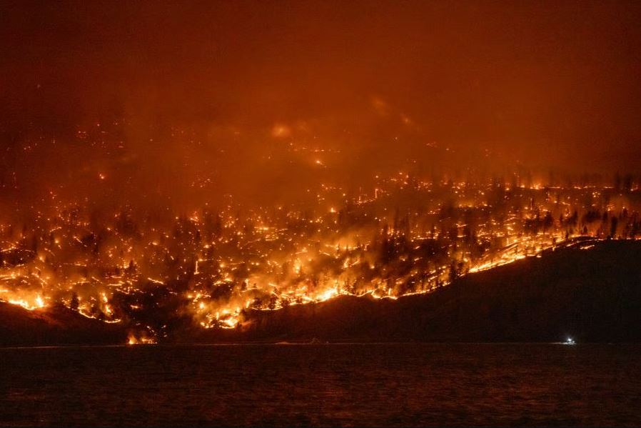 <who>Photo Credit: KelownaNow</who>The McDougall Creek wildfire burns on the hill above Westside Road in August 2023.