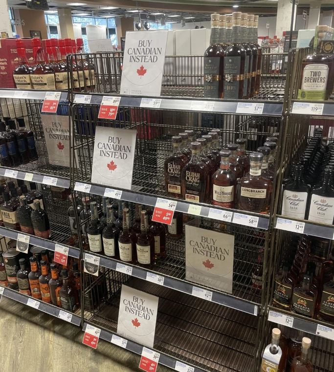 <who>Photo credit: Reddit</who>Shelves left empty by removing American liquor filled with 'Buy Canadian Instead' signs.