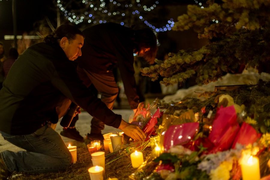 <who>Photo Credit: Tumbler RidgeLines/Facebook</who>A man places flowers at a vigil in Tumbler Ridge on Feb. 11.