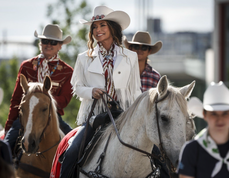 <who> Photo credit: Canadian Press </who> Parade Marshal Shania Twain, centre, rides a horse during the Calgary Stampede parade in Calgary, Friday, July 4, 2025.